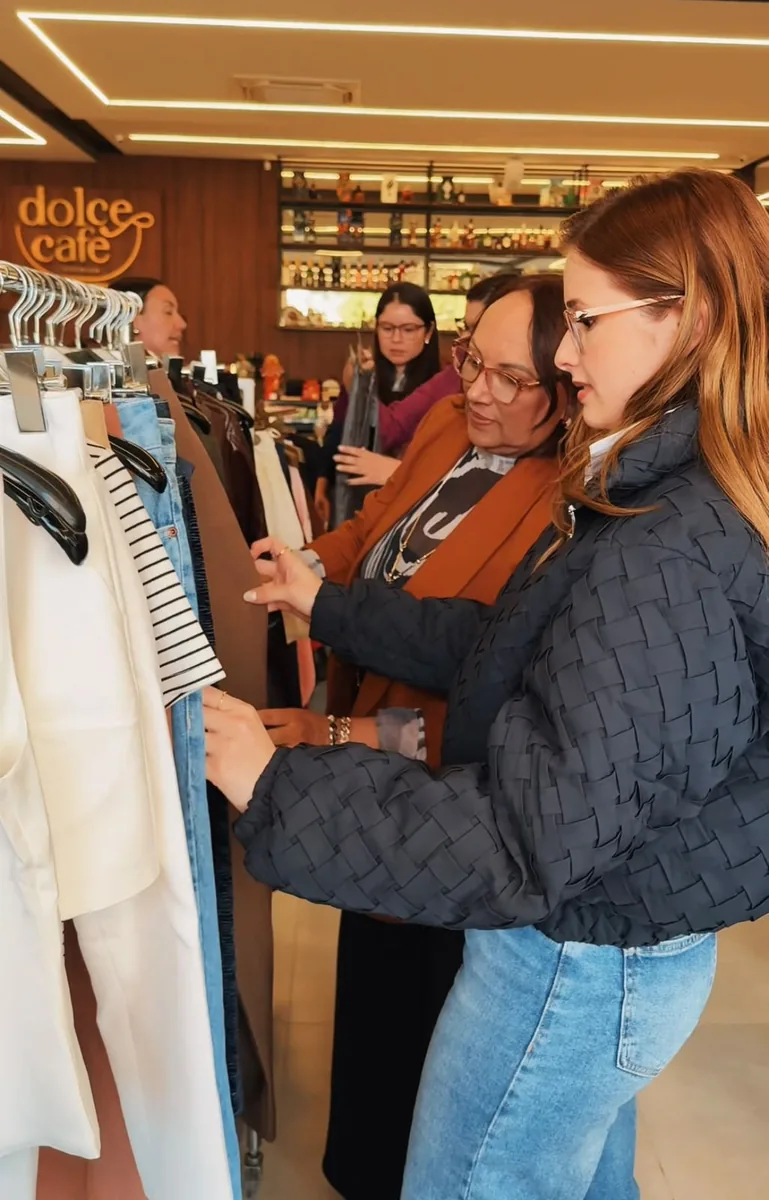 Participantes analisando roupas em arara durante atividade prática do curso
